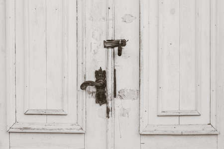 Old distressed white doors close up with black metal handle and lockの写真素材