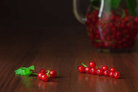 Close up with red currants berries with glass jug of detox water on wooden table. Copy space backgroundの写真素材