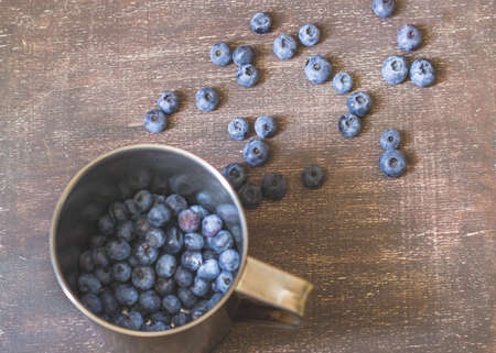 Blueberries in metal mug on wooden backgroundの写真素材