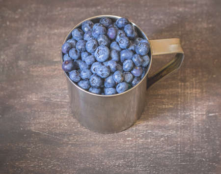 Blueberries in metal mug on wooden backgroundの写真素材
