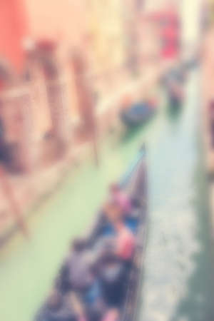 Defocused Background with Gondola full of People enjoying a cruise in a narrow water canal between old buildings in Venice, Italy.の写真素材
