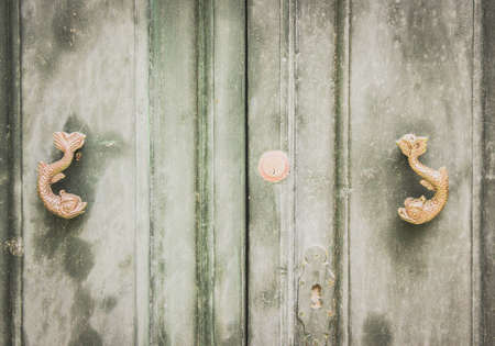 A Pair of Old Dolphin Shaped Metal Knockers on Green Wooden Distressed Doors in Mdina, Maltaの写真素材