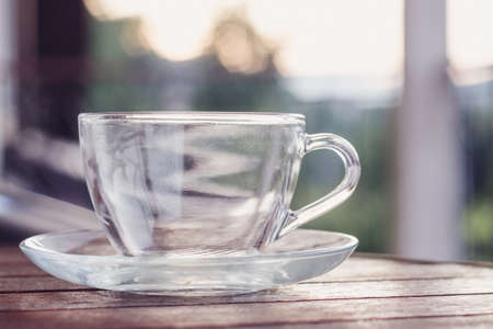 Glass tea cup on the round wooden table outdoor in the morning lightの写真素材