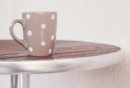 Grey polka dot cup on the round wooden tableの写真素材