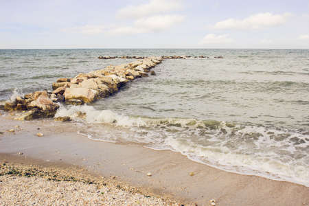 Sea view with a long stone pier at the Adriatic Sea shores in Italyの写真素材