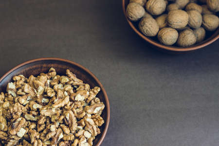 Walnut kernels and whole walnuts in brown ceramic bowls. Healthy organic food concept.の写真素材