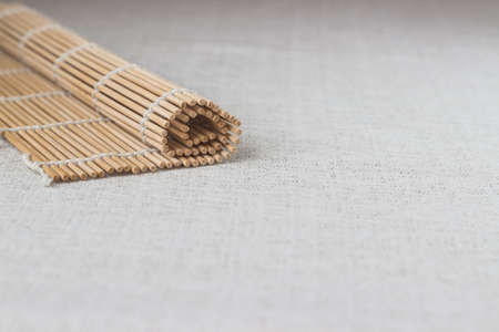 Wooden sushi chopsticks with rolled bamboo straw mat, space for textの写真素材