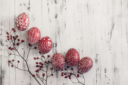 Decorated Easter eggs using a traditional in Eastern Europe wax-resist method and modern patterns. Still life with Pysanka, dry plants and lace on whitewashed wooden background, top view, copy spaceの写真素材
