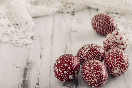 Decorated Easter eggs using a traditional in Eastern Europe wax-resist method and modern patterns. Still life with Pysanka, dry plants and lace on whitewashed wooden backgroundの写真素材