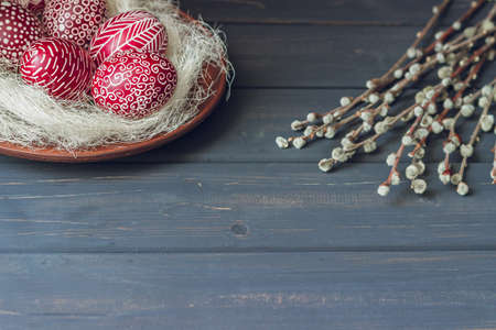 Still life with Pysanka, decorated Easter eggs, dry willow branches on black wooden background, copy...