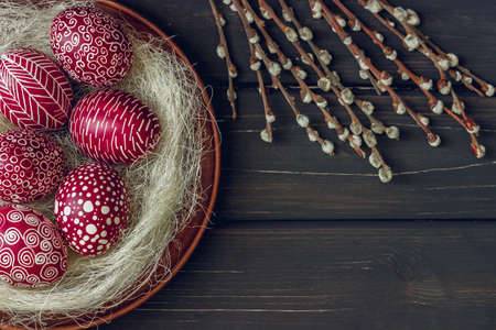 Still life with Pysanka, decorated Easter eggs, dry willow branches on black wooden background, top view, copy spaceの写真素材
