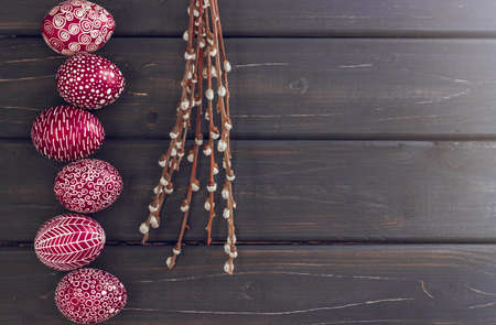 Still life with Pysanka, decorated Easter eggs, dry willow branches on black wooden background, top view, copy spaceの写真素材