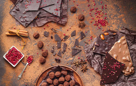 Assortment of chocolate bars, truffles, spices and cocoa powder on dark background. Space for text,...