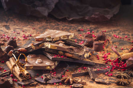 Assortment of chocolate bars, truffles, spices and cocoa powder on dark background