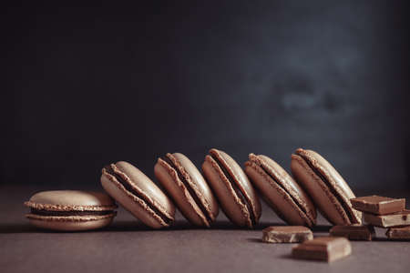 Row of Chocolate pastel brown Macarons or Macaroons over dark backgroundの写真素材