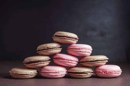 Pyramid of Chocolate and Raspberry pastel colored Macarons or Macaroons over dark background