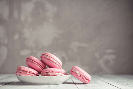 Raspberry pastel pink Macarons or Macaroons on a plate over concrete stone background