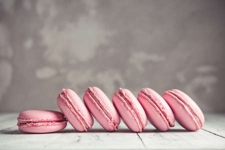 Row of Raspberry pastel pink Macarons or Macaroons over concrete stone backgroundの写真素材