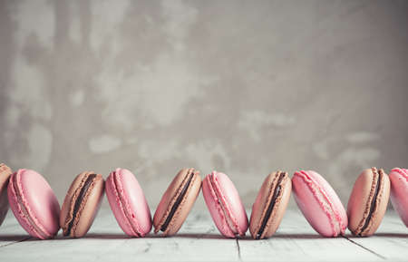 Row of Raspberry and Chocolate pastel colored Macarons or Macaroons over concrete stone backgroundの写真素材