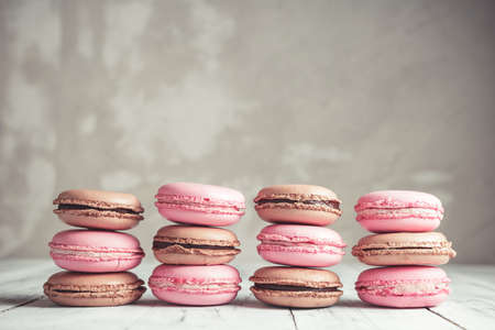 Stack of Raspberry and Chocolate pastel colored Macarons or Macaroons over concrete stone background
