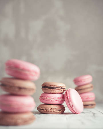 Stack of Raspberry and Chocolate pastel colored Macarons or Macaroons over concrete stone background