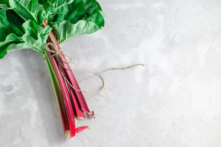Fresh organic rhubarb stems with leaves on grey concrete stone background. Space for your textの写真素材