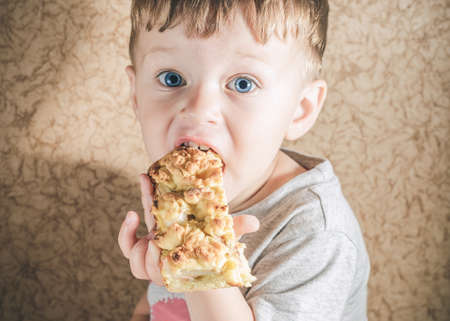 Toddler boy eating a big piece of homemade pieの写真素材