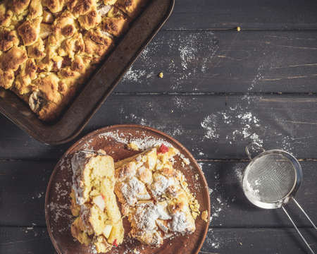Rustic style pie iced with sugar powder over black wooden background
