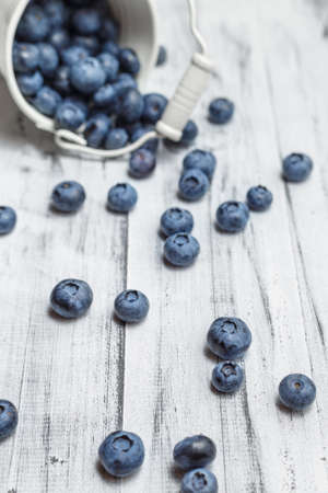 Blueberries in metal white bucket on white wooden backgroundの写真素材