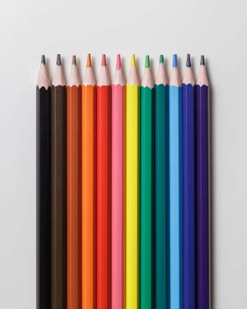Line of 12 colour pencils on grey background. Top view
