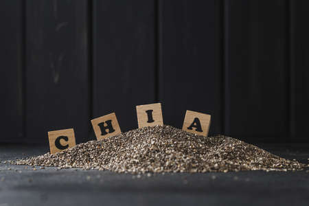 Heap of healthy organic chia seeds rich in omega-3 fatty acids over dark backgroundの写真素材