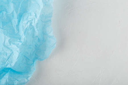 Blue crumpled paper border over white textured backgroundの写真素材