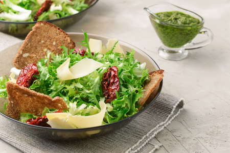 Salad with frisee lettuce, sun dried tomatoes, cheese, bread chips and pesto dressingの写真素材