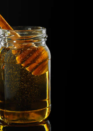 Honey jar with dipper on the black background, macro shot, vertical compositionの写真素材