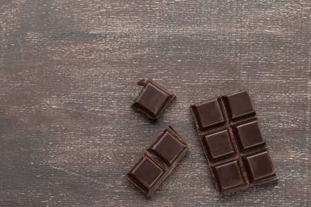Dark chocolate bar broken on a wooden backgroundの写真素材