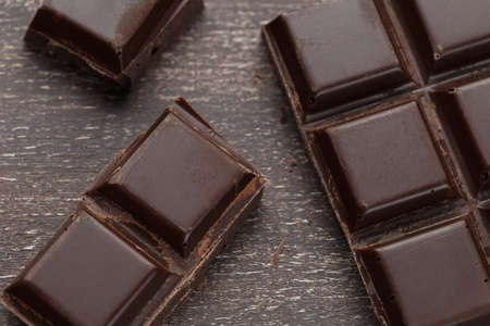 Dark chocolate bar broken on a wooden backgroundの写真素材