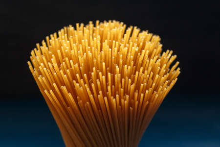 Bunch of uncooked Italian pasta spaghetti on a dark background. Macro shot, selective focusの写真素材
