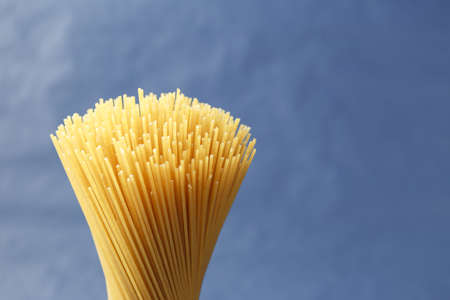 Bunch of uncooked Italian pasta spaghetti on a purple background with copy spaceの写真素材