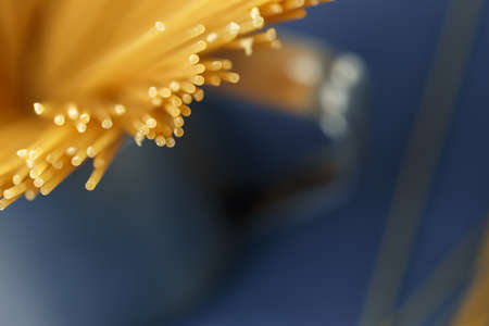 Bunch of uncooked Italian pasta spaghetti on a purple background. Macro shot, selective focus