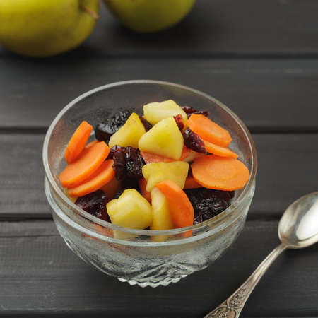 Tzimmes or tsimmes in a vintage glass bowl on the dark wooden table. A traditional Ashkenazi Jewish sweet stew made of carrot, apples, honey and dried fruitsの写真素材