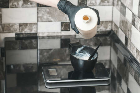 Hair stylist pouring an oxidant cream into the bowl preparing a coloring dyeの写真素材