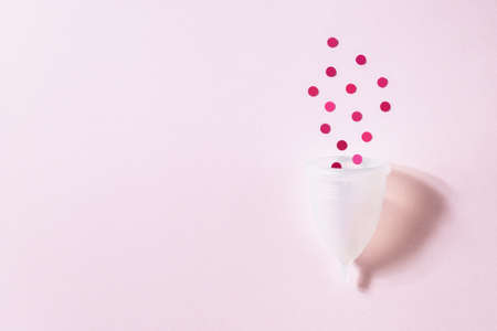 Menstrual cup on pink background. Alternative environmentally friendly feminine hygiene product to collect blood during the period inside the vagina. Women health conceptの写真素材