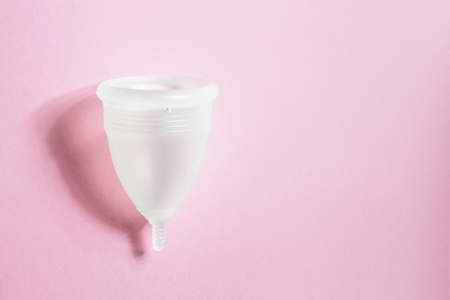 Menstrual cup on pink background. Alternative environmentally friendly feminine hygiene product to collect blood during the period inside the vagina. Women health conceptの写真素材