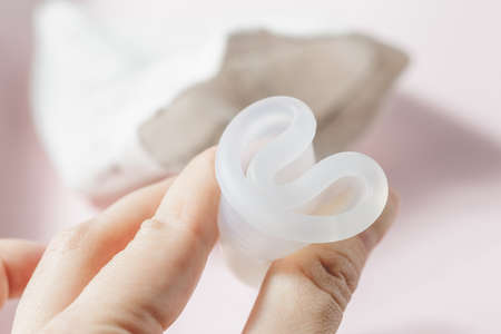 Close up of woman hand folding menstrual cup showing how to use, c form. Women health concept, zero...