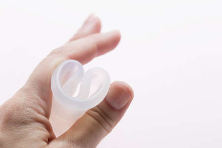 Close up of woman hand folding menstrual cup showing how to use, c form. Women health concept, zero...