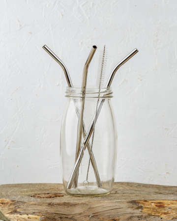 Three reusable metal drinking straws and cleaning brush in a jar over grey background. Zero Waste and minimalism lifestyleの写真素材