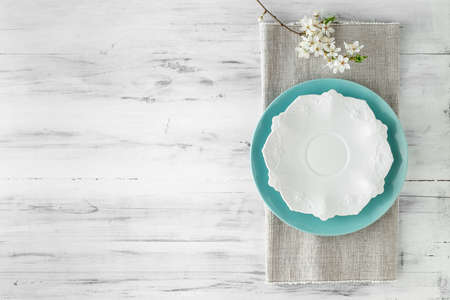 Spring table set with plates and blooming white flowers branch. top view with copy spaceの写真素材