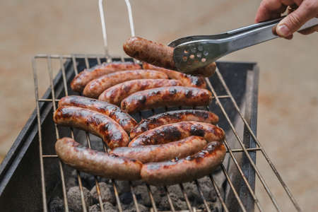 Grilling sausages on barbecue grill outdoor. Picnick in the park or forest. Selective focusの写真素材