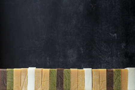 Bottom border of different kinds of handmade soap bars over black background. Copy space for text