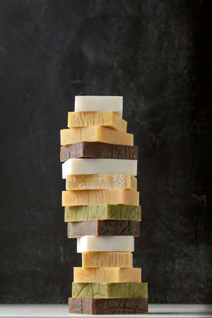 Tower stack of different kinds of handmade solid soap bars and shampoo over grey backgroundの写真素材